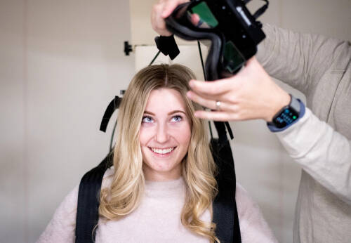 student smiles while wearing a piece of audiology equipment
